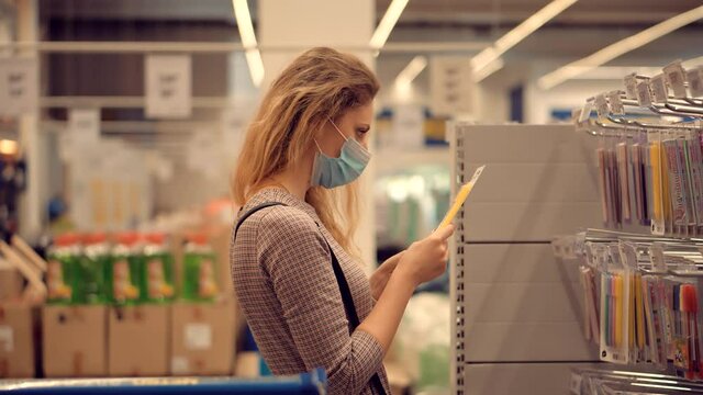 Woman Shopper Choosing Product In Hypermarket Store.Girl In Face Mask Shopping In Market On Covid19 Coronavirus Pandemic Quarantine Lockdown.Bayer In Medical Mask In Supermarket Avoid Self Distance