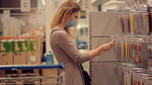 Woman Shopper Choosing Product In Hypermarket Store.Girl In Face Mask Shopping In Market On Covid19 Coronavirus Pandemic Quarantine Lockdown.Bayer In Medical Mask In Supermarket Avoid Self Distance