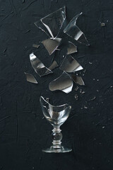 Smashed wineglass on a black background, top view