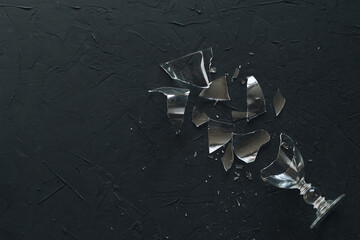 Broken wine glass on a black background. Top view with copy space