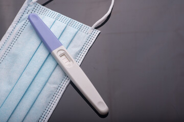 A pregnancy test kit with medical face mask,isolated over various background,conception during pandemic concept