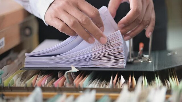 A businessman searching for financial and accounting documents in an office file cabinet