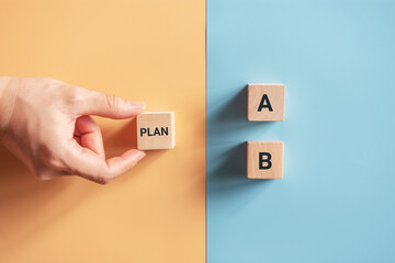 Hand choose wooden cube with the word PLAN A to PLAN B on blue and yellow background. Business...