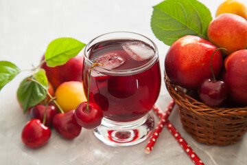 cherry juice in a glass, berries and fruit on a table, selective focus