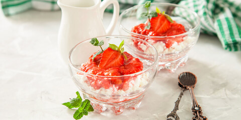 summer breakfast - cottage cheese with strawberry in a glass bowl on a table, selective focus