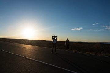 Fototapeta na wymiar Silhouette of a guy on the road taking photos at dawn