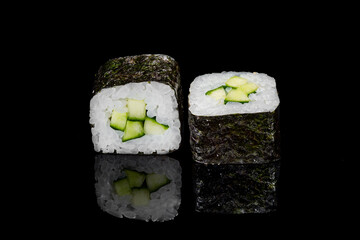 Sushi and rolls on a black mirrored background.