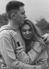 A girl hugs a guy in black. A girl and a guy in identical sweatshirts at the stadium