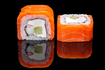 Sushi and rolls on a black mirrored background.
