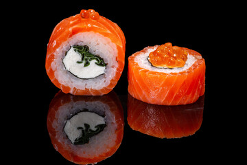 Sushi and rolls on a black mirrored background.