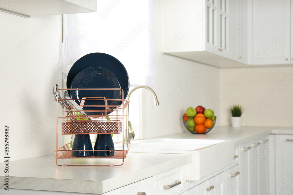 Sticker Drying rack with clean dishes on countertop in kitchen. Space for text