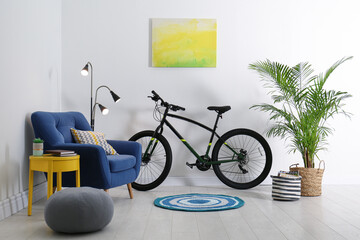Modern bicycle and comfortable armchair in stylish living room interior