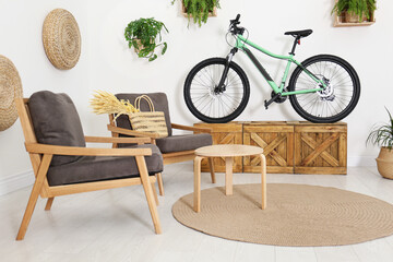 Modern bicycle and comfortable armchairs in stylish living room interior