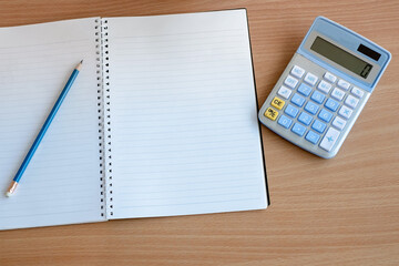 Stationary and blank books on the table, pencil set ,cup of coffee and calculator on wood table , copy space of stationary , working space, space work from home