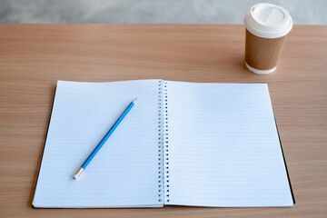 Stationary and blank books on the table, pencil set ,cup of coffee and calculator on wood table , copy space of stationary , working space, space work from home