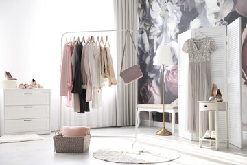 Rack with stylish women's clothes and handbag indoors. Interior design