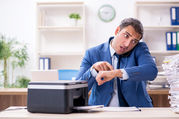 Young male employee making copies at copying machine