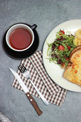 
Quesadilla bread on a plate with healthy vegetables and a cup of tea in a glass. Top view