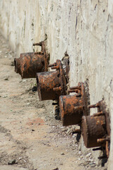 Vertical photograph of fragments of old rusty iron pipes at the bottom of a dry pool