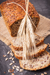 Obraz premium Wholegrain bread for breakfast, ingredients for baking and ears of rye or wheat grain