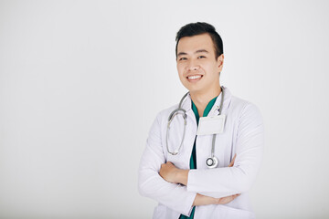 Portrait of hapy smiling young Vietnamese doctor crossing arms and looking at camera, isolated on shite