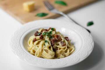 Traditional Italian pasta fettuccine alfredo with sun-dried tomatoes and basil made vegan. Sauce made with bechamel, plant-based milk, olive oil and garlic.