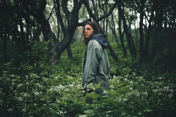 back view of a girl walking along a path through a gloomy mystical foggy forest. Journey and outdoor concept.