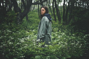 back view of a girl walking along a path through a gloomy mystical foggy forest. Journey and outdoor concept.