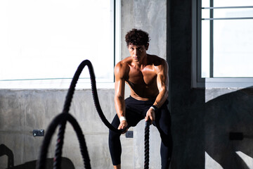 Fitness and sports man training with battle rope in cross fit gym. Fitness Healthy lifestye and workout at gym concept.