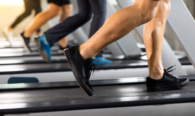 Fototapeta na wymiar Man running on treadmill machine at gym sports club. Fitness Healthy lifestye and workout at gym concept. Selective focus at mele shoe.