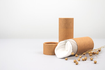 Front view on paper tubes with white cotton disks inside on light grey background with copyspace. Reusable packaging and recycling concept showing how to reuse cardboard packaging at home. Mockup