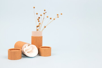 Paper tubes with white cotton disks inside on light blue background with copyspace. Reusable packaging and recycling concept showing how to reuse cardboard packaging at home. Mockup