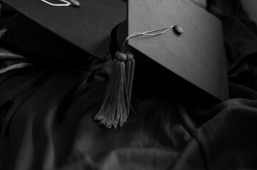 closeup, black graduated hat and black tassel, placed on a monotone black dress