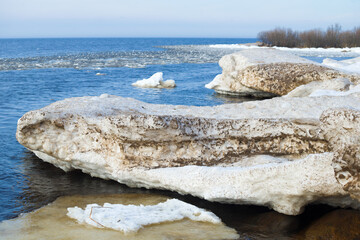 Melted blocks of snow on the shore of Ladoga lake on a spring day. Leningrad region, Russia