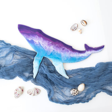 Resin art whale with fabric waves on white. Flat lay, top view