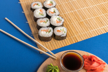 Sushi rolls set served on bamboo mat. Blue background