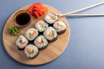 Fesh rolls with cucumber and salmon on a wooden board