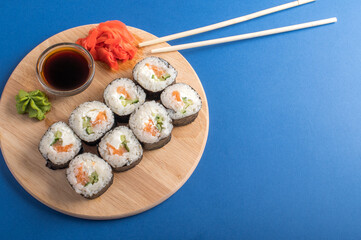 Fesh rolls with cucumber and salmon on a wooden board