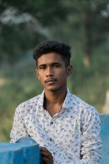 outdoor portrait of a young guy wearing white shirt looking at the camera