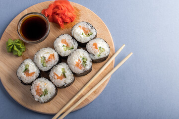 Fesh rolls with cucumber and salmon on a wooden board