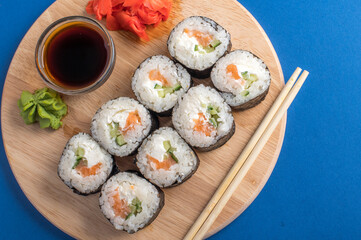 Fesh rolls with cucumber and salmon on a wooden board