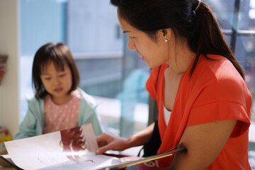 Fototapeta premium Asian Chinese Mother and Daughter reading books in the library