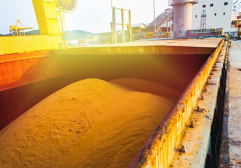 Raw sugar bulk loaded into large vessel hole for export. Sugar bulk products transport and handling. Agro-industry concept.