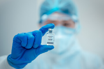 Scientist or researcher hand in blue gloves holding flu, measles, coronavirus, covid-19 vaccine disease preparing for human clinical trials vaccination shot, medicine and drug concept.