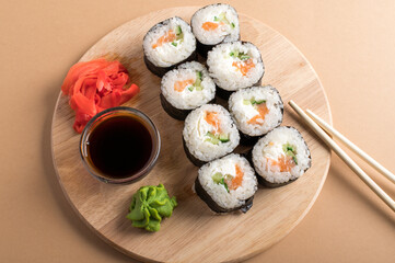 Sushi rolls set served on wooden board. Beige background