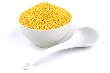 White bowl with a white spoon on a white background with a hill of millet groats
