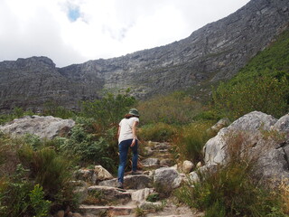 Naklejka na ściany i meble A woman walking along the mountain path leading to the top of Table Mountain, Cape Town, South Africa