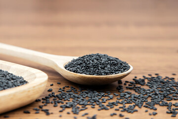Black sesame seeds in a wooden spoon.