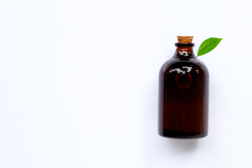 Essential oil bottle with green leaf on white background.