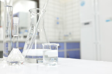 Chemistry Science laboratory  flask, beaker and glassware with clear liquid chemical in blur...